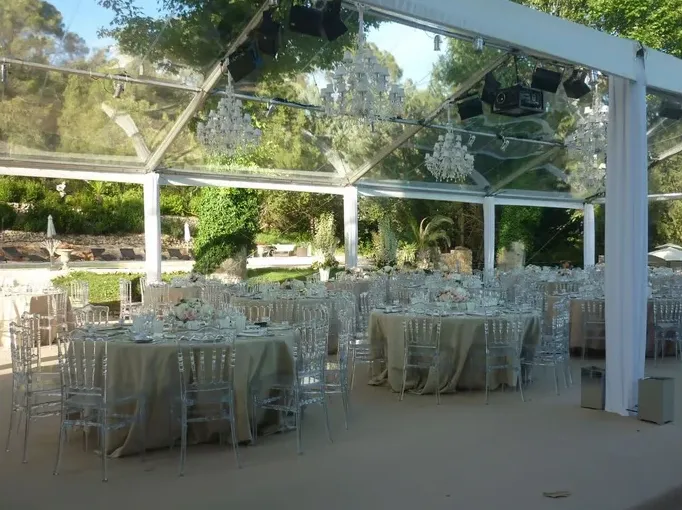 Un dîner sous un chapiteau transparent garni de lustres en cristal, dans le parc