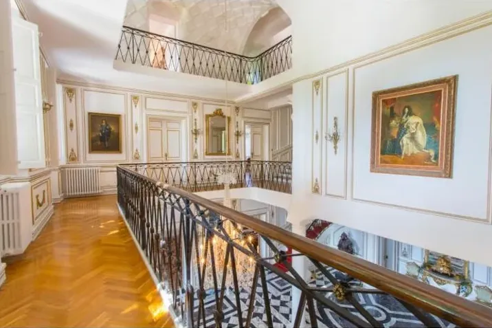 La galerie en fer forgé au-dessus du hall dallé de marbre
