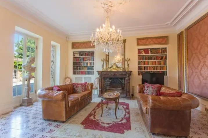 Le salon-bibliothèque, ses canapés Chesterfield et son lustre en cristal
